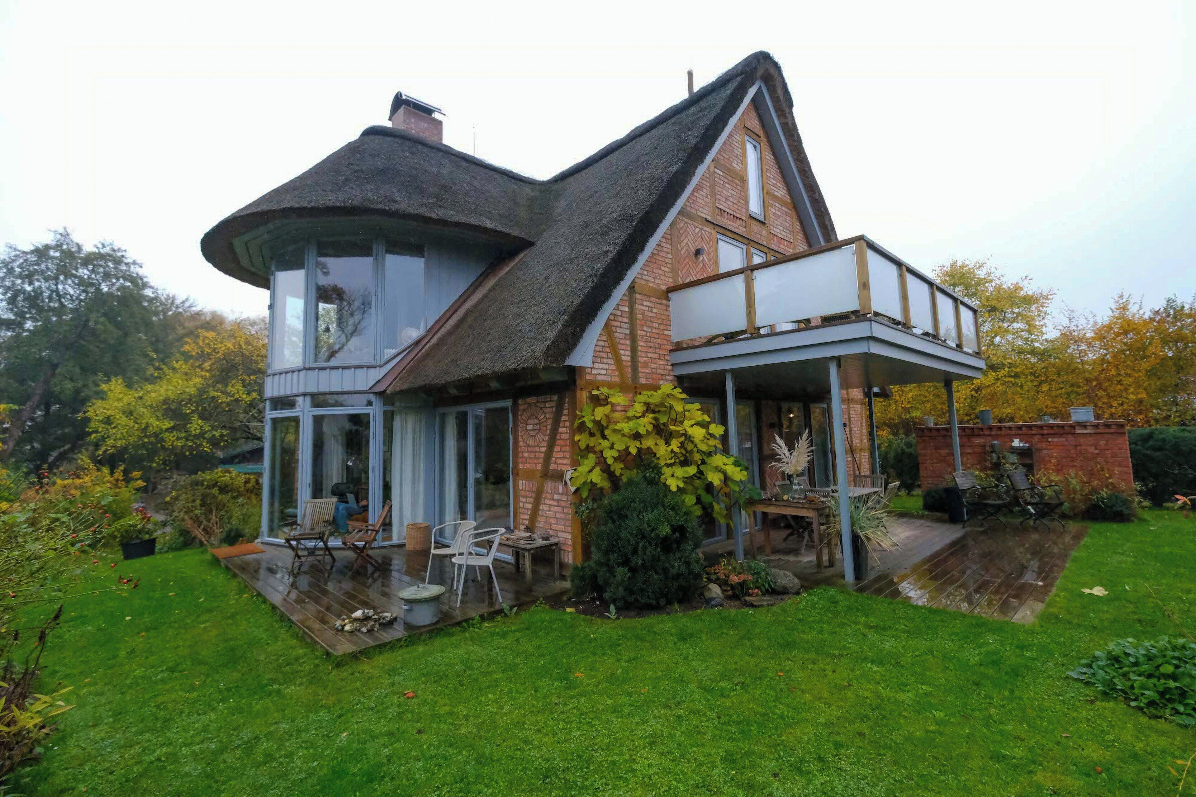 Ein Haus mit einem bogenförmigen Glaserker, einer Ziegelaußenwand und einer Holzdielen-Terrasse.