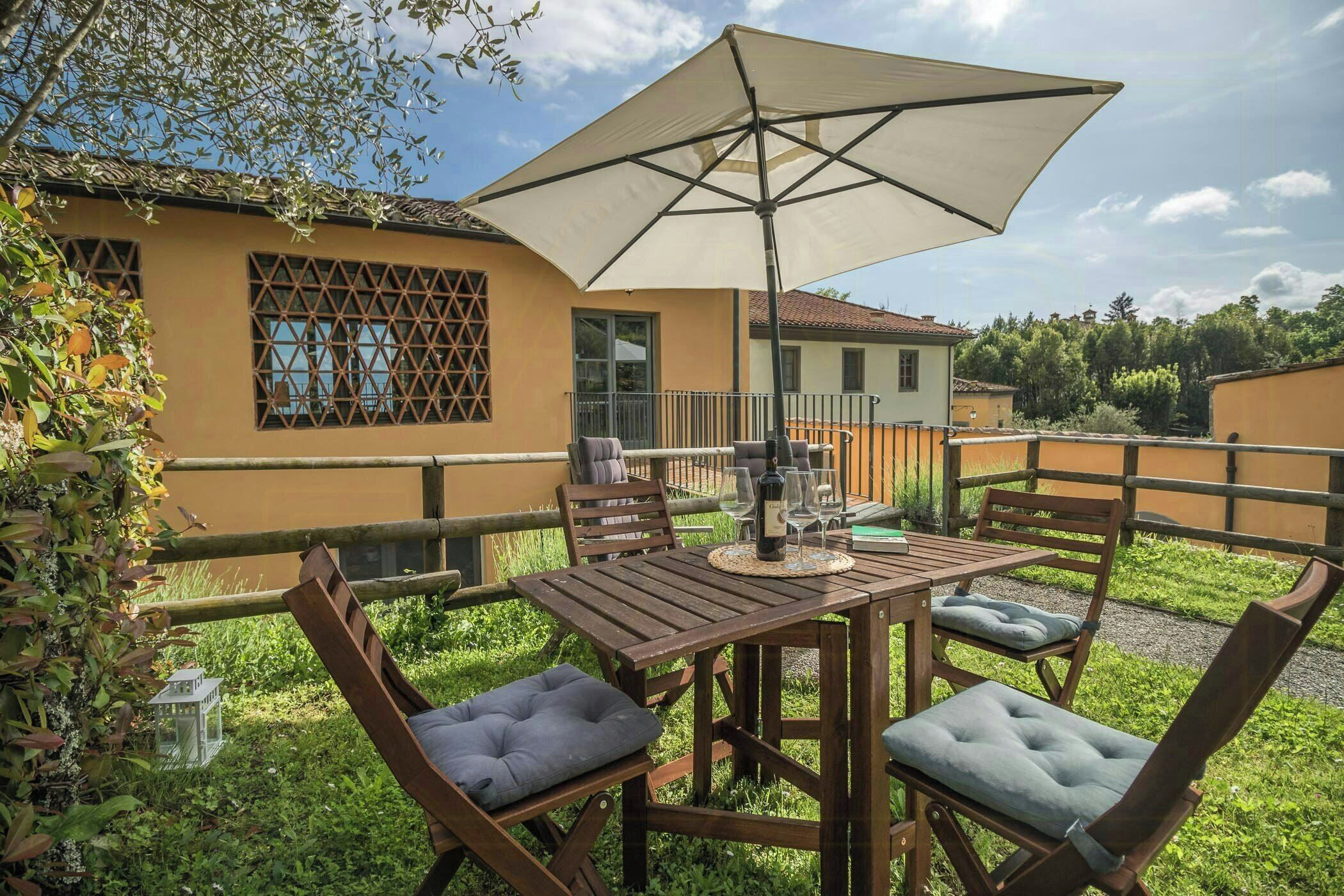 A wooden table with chairs and a large umbrella in an outdoor setting.