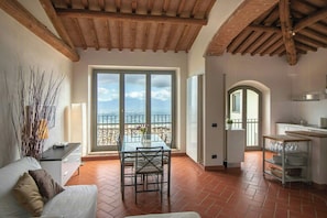 Ein Zimmer mit Esstisch, Stühlen, einer Sitzecke und einer Küchenzeile, sowie einem Balkon mit Blick.