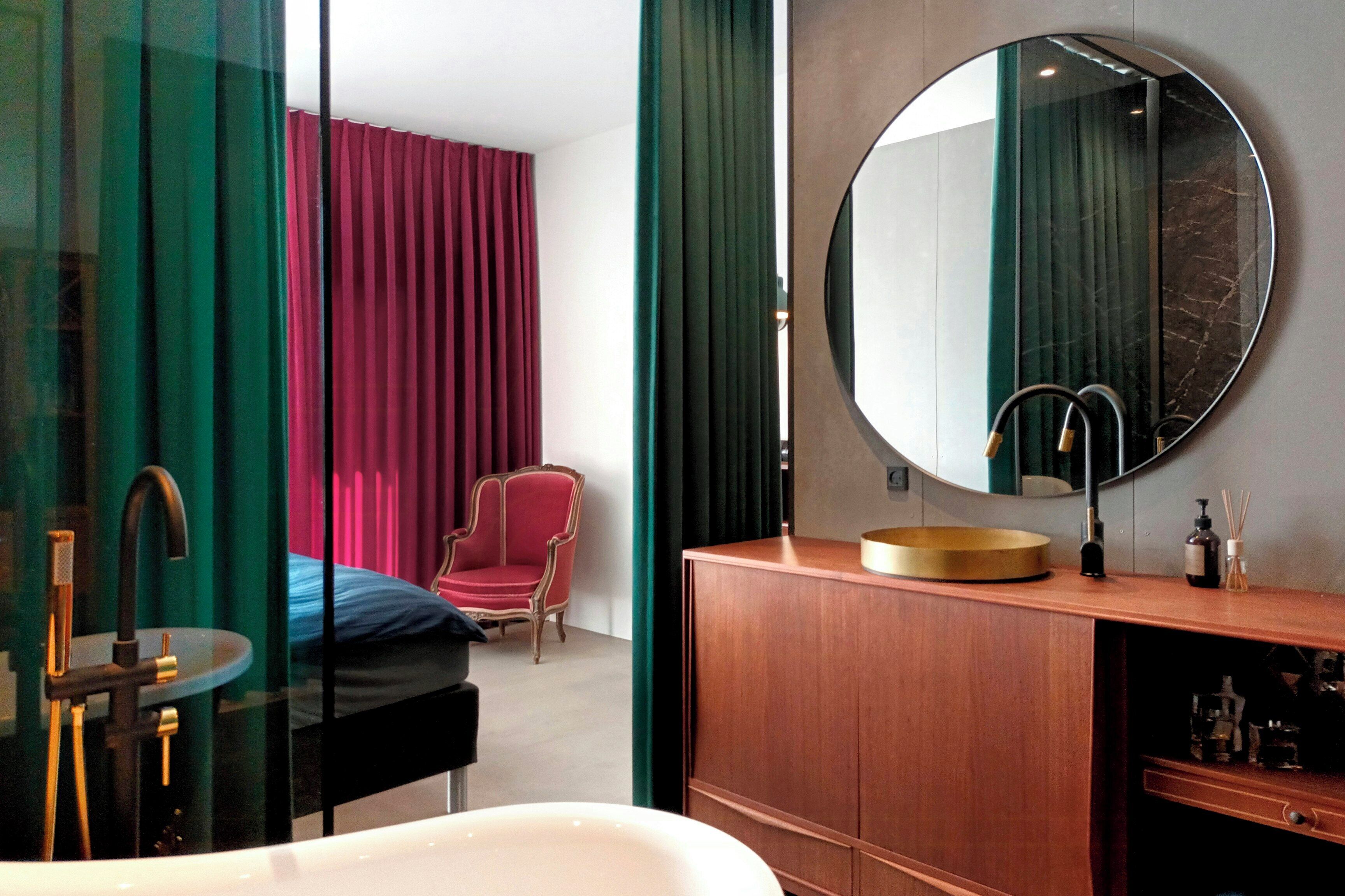 Ein modernes Badezimmer mit einem runden Spiegel, einer weißen Badewanne und einem Holzbadezimmer.