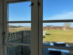 Une vue à travers une fenêtre, avec une clôture en bois, une table de pique-nique et un bâtiment au loin.