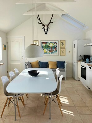 A modern kitchen with a dining area, a ceiling-mounted deer skull, and a large abstract painting. - House in peaceful surroundings 150 m to the water (Asperup)