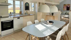 A modern kitchen with a Beko oven, a sink, and a dining area with a white table and chairs. - House in peaceful surroundings 150 m to the water (Asperup)
