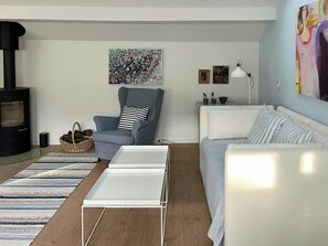 A living room with a sofa, a chair, a fireplace, a painting, and a lamp. - House in peaceful surroundings 150 m to the water (Asperup)
