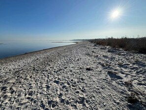 Une plage de sable avec des empreintes et un ciel dégagé.