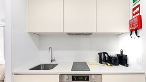 A modern kitchen with a stainless steel sink, a black induction cooktop, a coffee maker, and a kettle.