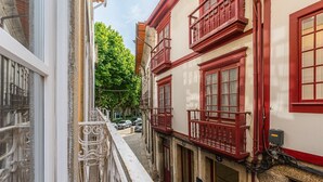 A narrow street with buildings featuring red balconies and white walls.