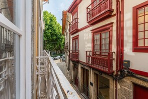 Eine enge Straße mit Gebäuden, die rote Balkone und weiße Wände haben.