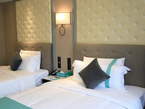 A hotel room with two beds, a wall-mounted light, a control panel, and a bedside table with a phone and a tissue box. - Pai Hotel (Chongqing)