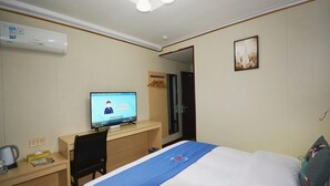 Habitació d'hotel amb un llit, una taula de treball amb un ordinador, un mirall i un aire acondicionador fixat a la paret.