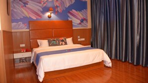 Habitació d'hotel amb un llit gran, un capçal de llit, una tauleta de nit, una làmpada i un mural a la paret.