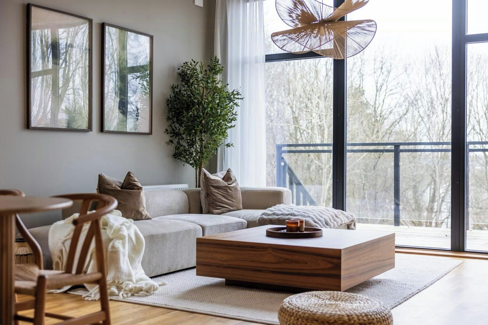A modern living room with a sofa, coffee table, and a large window with a view of trees.