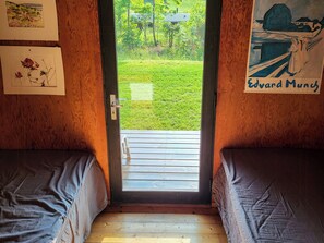 Ein Zimmer mit zwei Betten, einer zur Außenseite führenden Tür und Bildern an den Wänden.