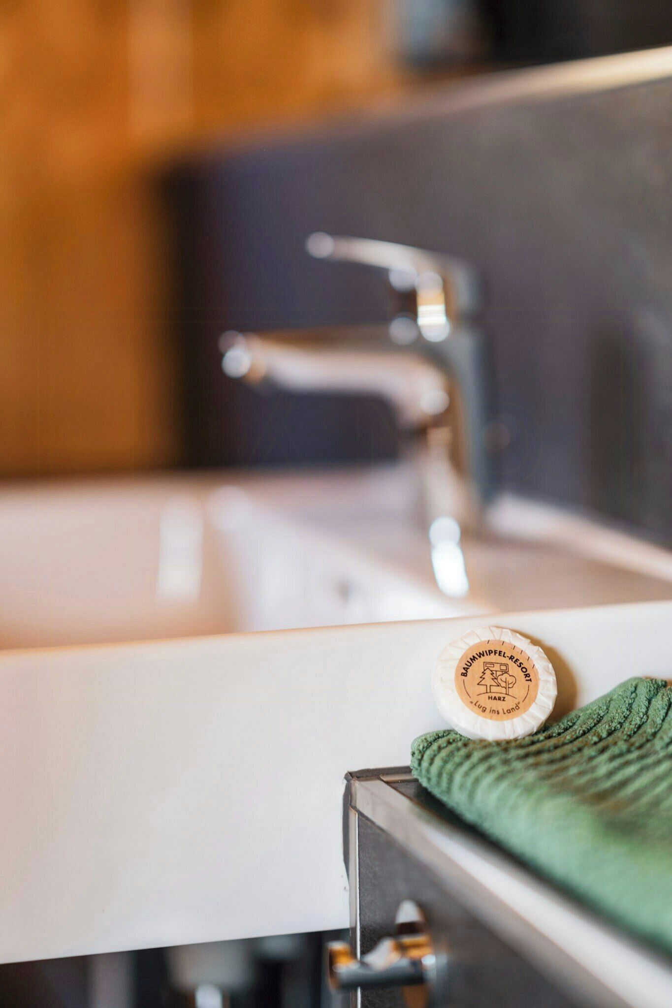Un lavabo de baño con una toalla verde y un jabonera.
