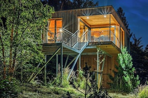 Eine moderne Holzhütte mit Balkon, umgeben von Bäumen.