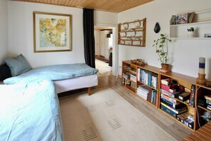 Ein Schlafzimmer mit einem Bett, einem Bücherregal, einer Topfpflanze und einem Bild an der Wand.