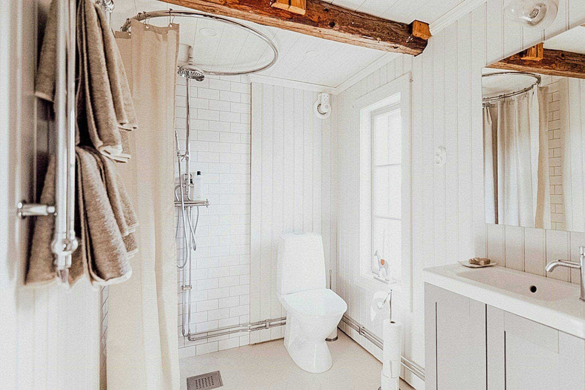 A bathroom with a shower, toilet, sink, and towel rack.