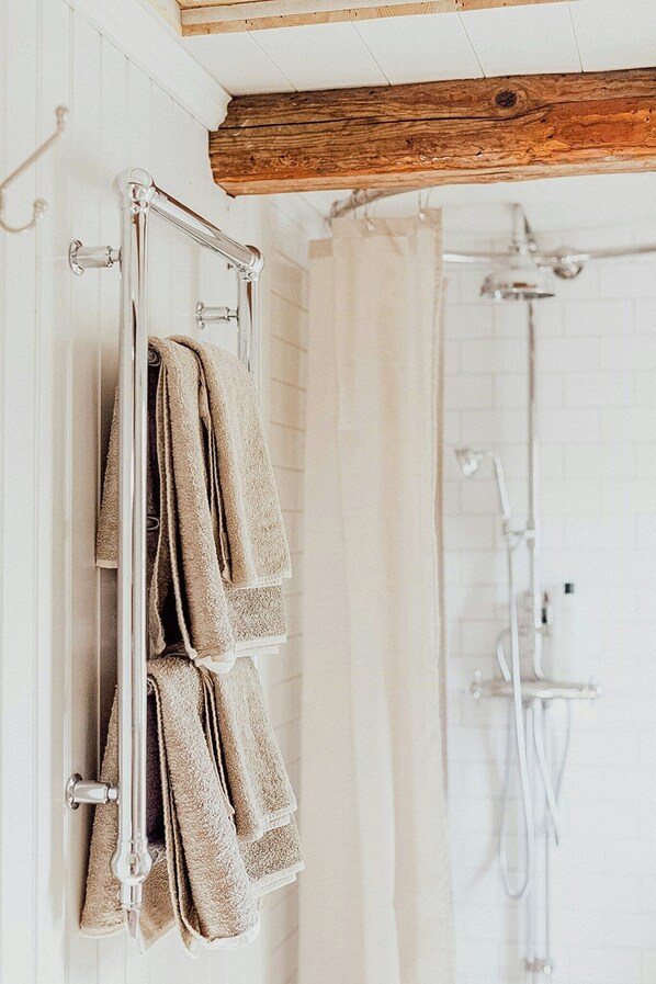 Une salle de bain équipée d’un porte-serviettes, d’une douche et de poutres en bois au plafond.