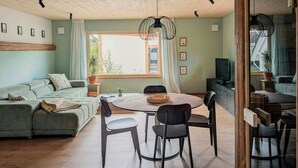 A modern living room with a sofa, dining table, chairs, and a TV. - Loft apartment with sauna in the Haßberge (Hofheim in Unterfranken)