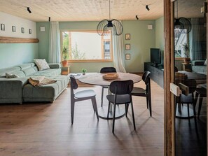 Ein modernes Wohnzimmer mit einer Couch, einem Esstisch, Stühlen und einem Fernseher.