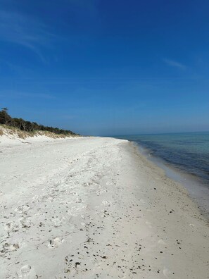 Ein Strand mit weißem Sand und klarem, blauem Wasser.