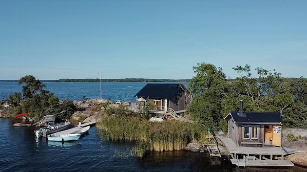 A lakeside cabin with a dock, a small boat, and a pier. - Island house on private island with sea view (Östhammar)