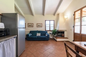 A compact living space with a kitchenette, a sofa, a dining table, and a fireplace. - Tuscan villa with pool in the heart of Tuscany (Bucine)
