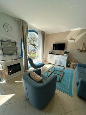 A living room with a sofa, armchair, TV, fireplace, and a view of the outdoors. - Lakefront house with garden on Monte Isola (Monte Isola)