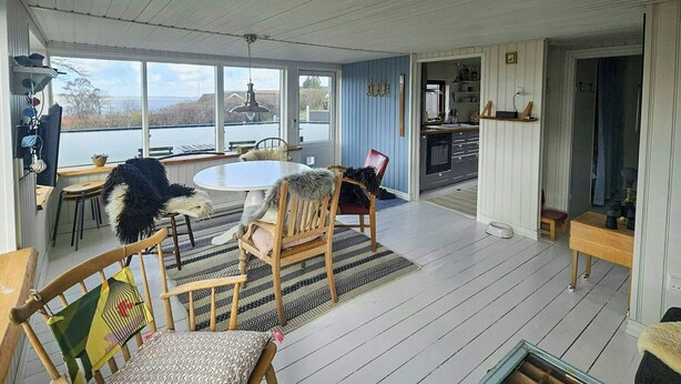 A spacious room with a large window, a round table, and several chairs. - Cozy cottage with fjord view in Hjarbæk (Løgstrup)