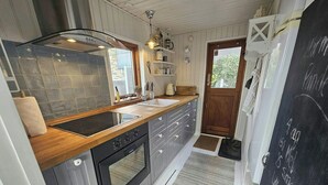 A compact kitchen with a wooden countertop, a built-in oven, and a chalkboard with writing. - Cozy cottage with fjord view in Hjarbæk (Løgstrup)