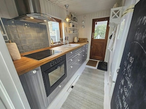 A compact kitchen with a wooden countertop, a built-in oven, and a chalkboard with writing. - Cozy cottage with fjord view in Hjarbæk (Løgstrup)