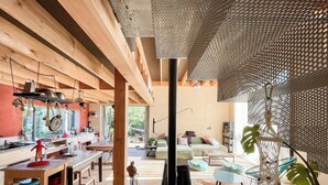 A spacious kitchen with wooden beams, a dining area with a table and chairs, a cozy living room with a sofa, and a large window providing natural light. - Natural materials house near Nancy (Dommartemont)