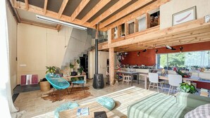 A spacious living area with a high ceiling, wooden beams, a kitchen with red walls, and a staircase leading to an upper level. - Natural materials house near Nancy (Dommartemont)