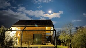 A modern house with a glass facade, a wooden exterior, and a visible porch area. - Natural materials house near Nancy (Dommartemont)