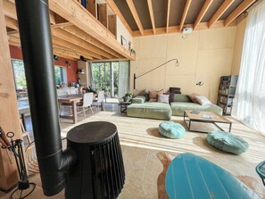 Un intérieur moderne avec un plafond en bois, un coin repas, un canapé vert et un radiateur noir.