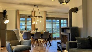 Una sala de estar moderna con chimenea, comedor y ventanas amplias.