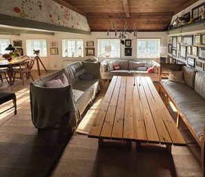 A cozy living room with a wooden table, sofas, and a bookshelf filled with framed pictures. - Protected farm from 1798 by Blåvand beach (Blåvand)