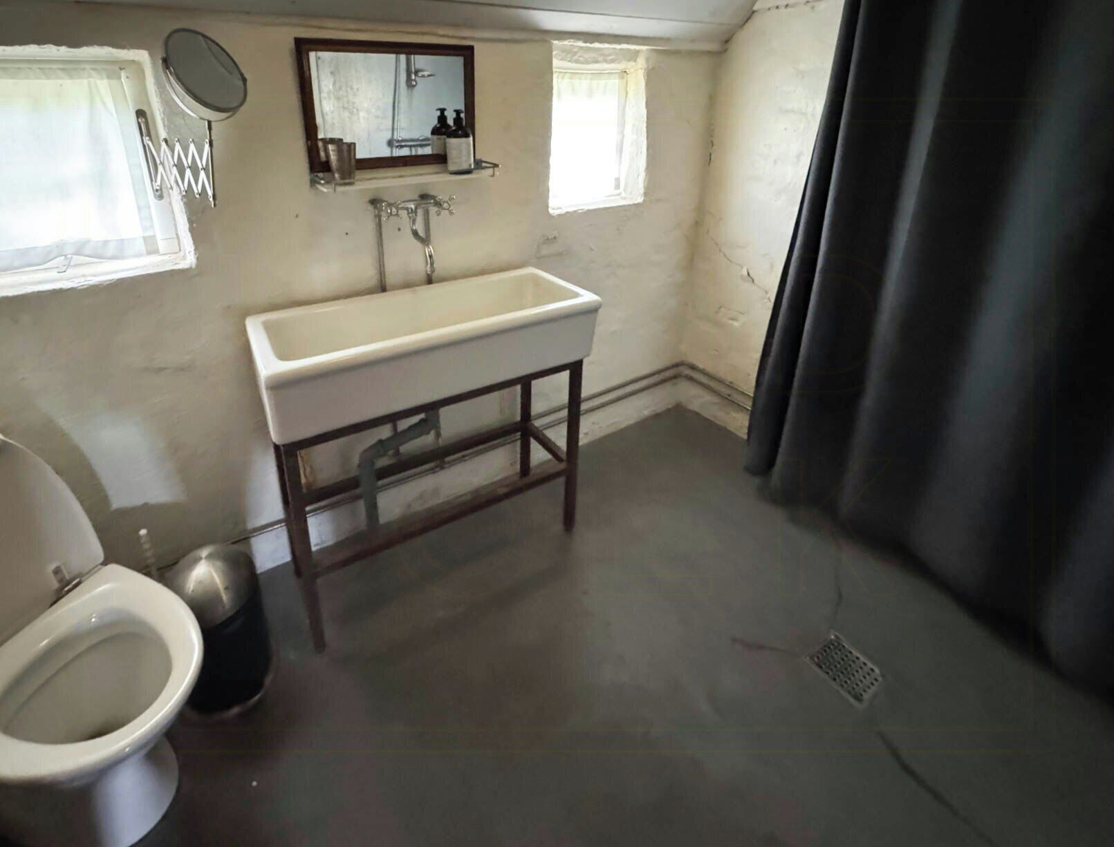 Une salle de bain équipée de toilettes, d’un lavabo, d’un miroir et d’une douche.