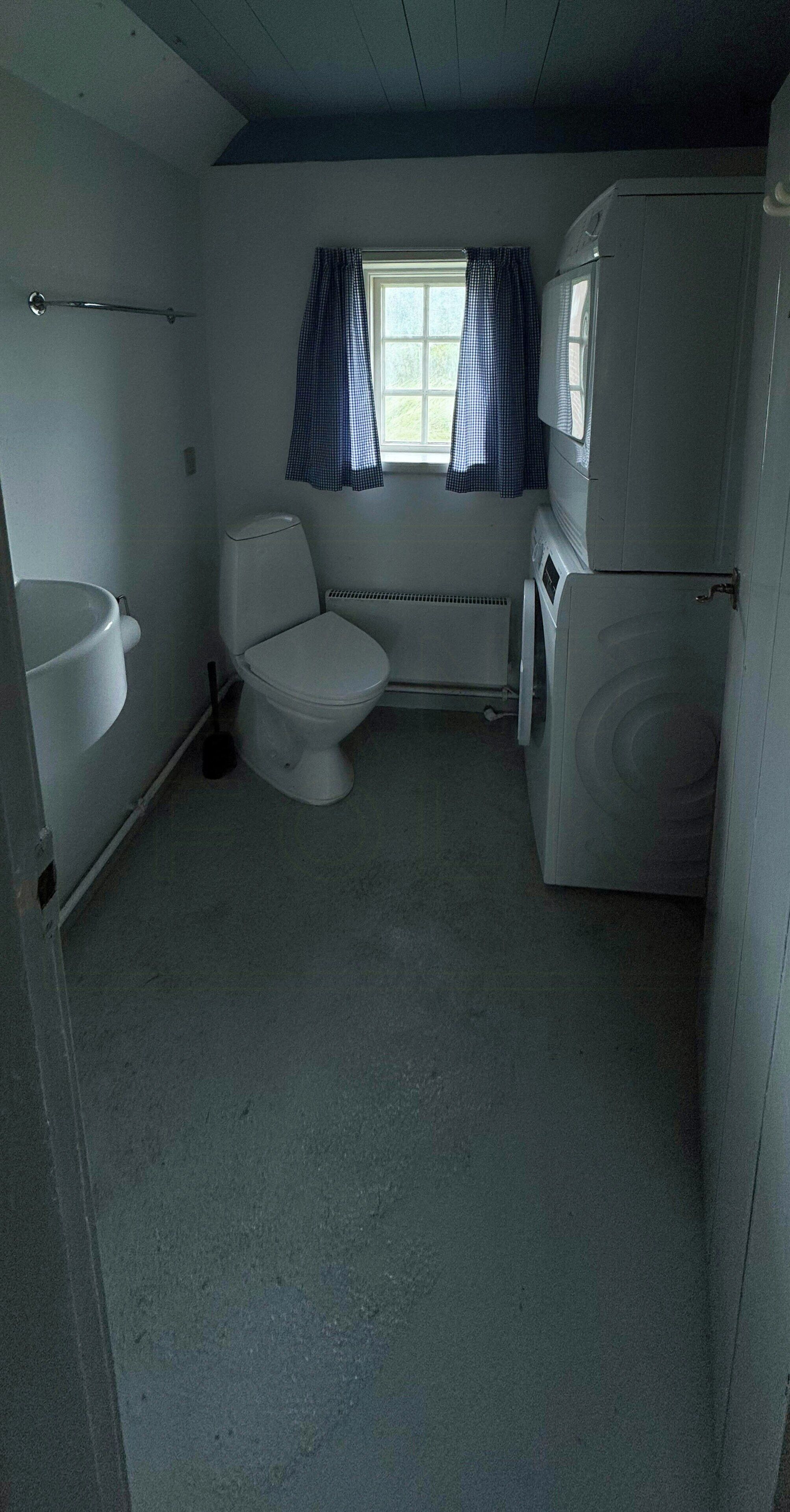 A compact bathroom with a toilet, sink, and washing machine.