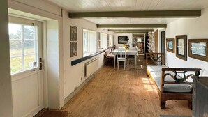 A hallway with wooden flooring, a dining area with a table and chairs, and a seating area with a bench. - Protected farm from 1798 by Blåvand beach (Blåvand)