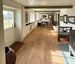 A hallway with wooden flooring, a dining area with a table and chairs, and a seating area with a bench. - Protected farm from 1798 by Blåvand beach (Blåvand)