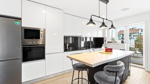 Una cocina moderna con electrodomésticos de acero inoxidable, una isla de madera y taburetes de bar.