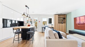 Una cocina moderna con una isla central, taburetes de bar e iluminación colgante.