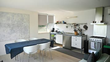 A compact kitchen with a dining area, a stove, and a window.