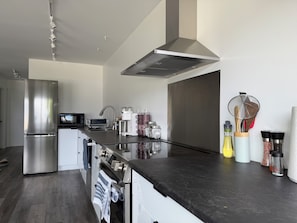 Una cocina moderna con un refrigerador de acero inoxidable, horno empotrado, microondas y cafetera.