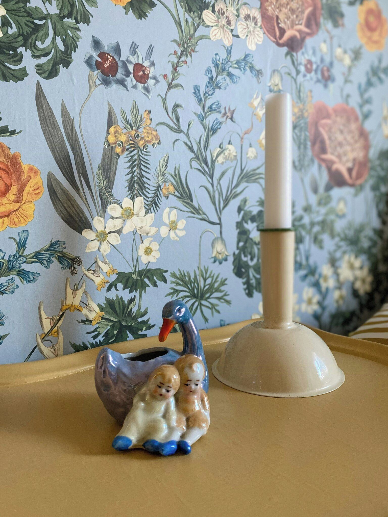 Una figurita de cerámica de un pato decorativo con dos polluelos sobre una bandeja.