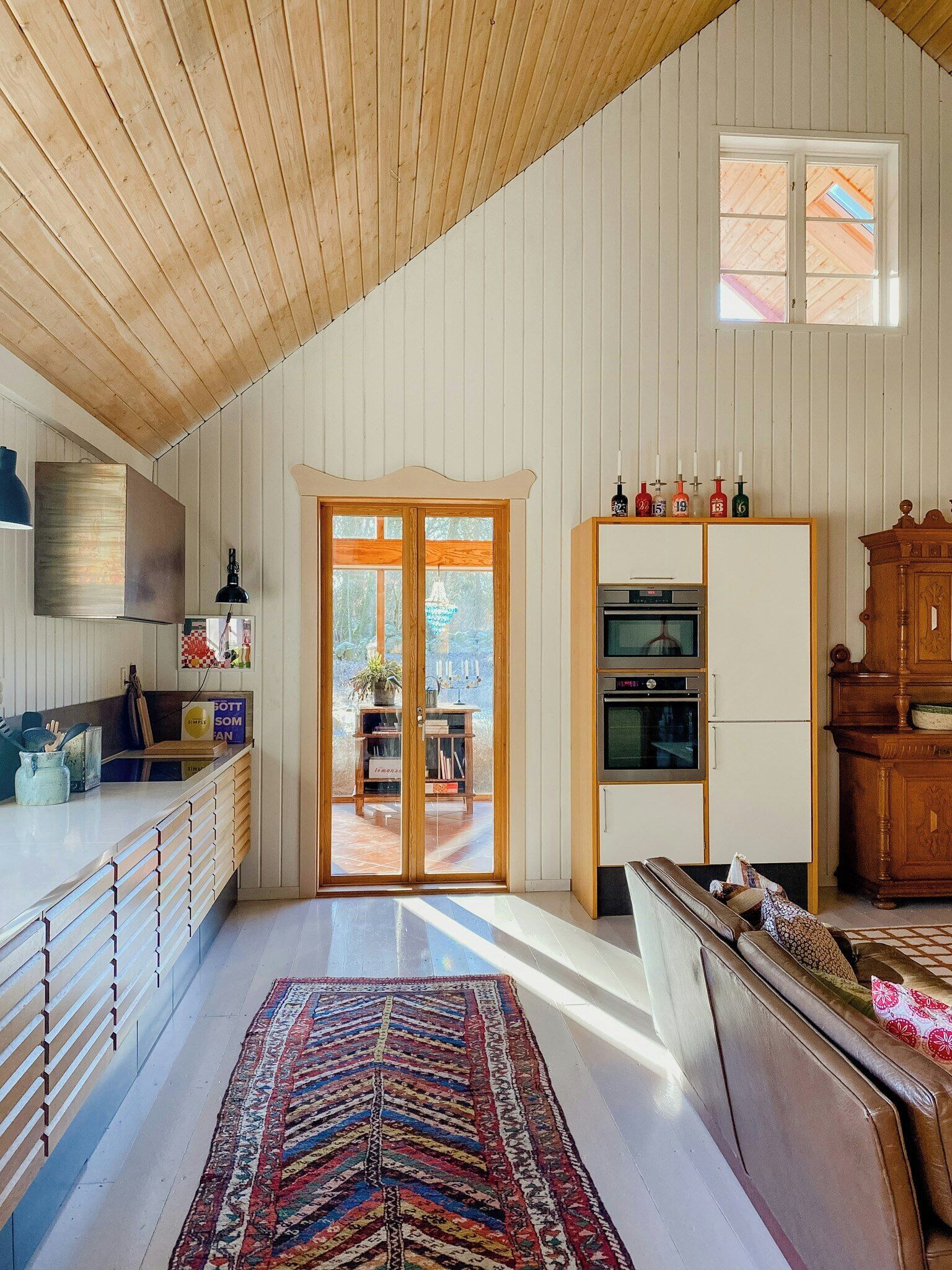 A spacious kitchen with wooden cabinets, a large window, and a dining area with a sofa.