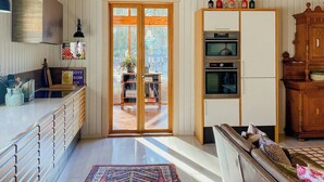Une cuisine spacieuse avec des meubles en bois, une grande fenêtre et un coin repas doté d’un canapé.