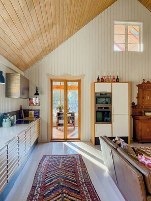 Eine geräumige Küche mit Holzschränken, einem großen Fenster und einem Essbereich mit einer Couch.