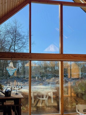 Ein Zimmer mit großen Fenstern, einer Holzbalkendecke, einem Tisch mit Stühlen und einer Kristallleuchter.